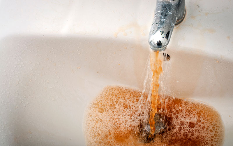 Dirty brown water running from a filthy faucet