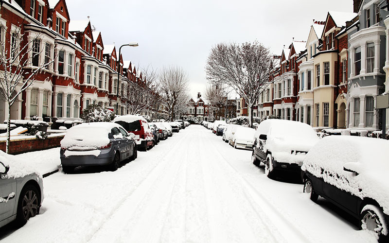 English road with cars on either side covered in deep snow